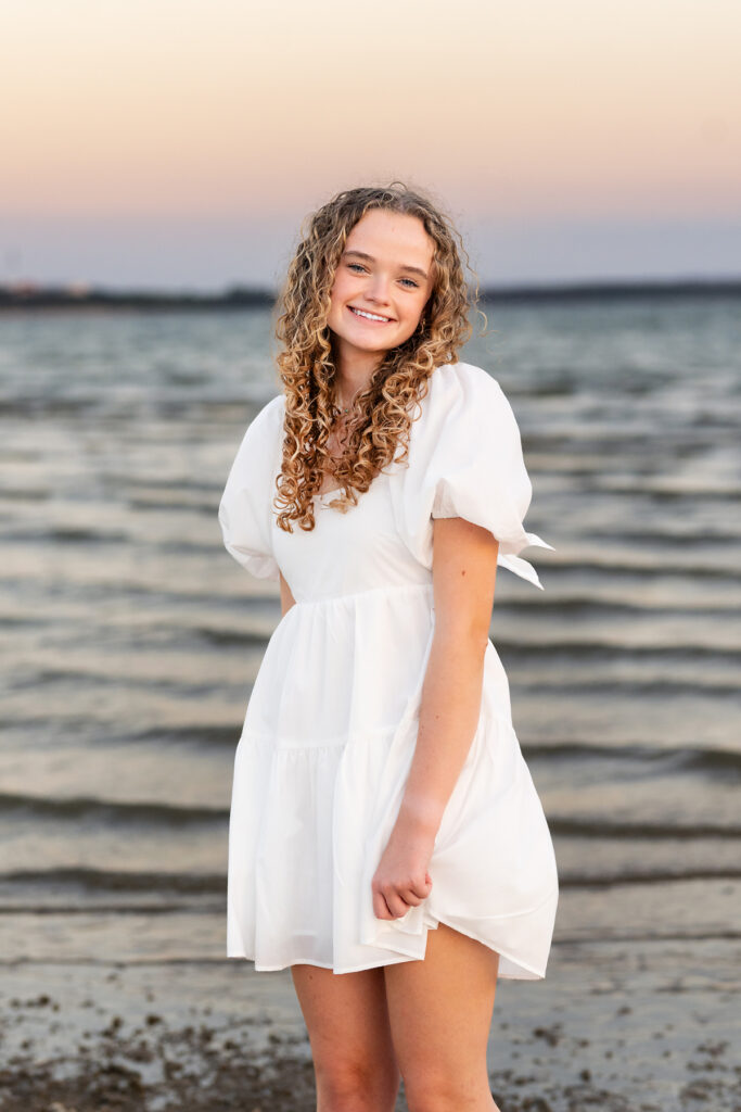 Senior girl in white dress posing for beach senior portraits by Paige Walker Photography