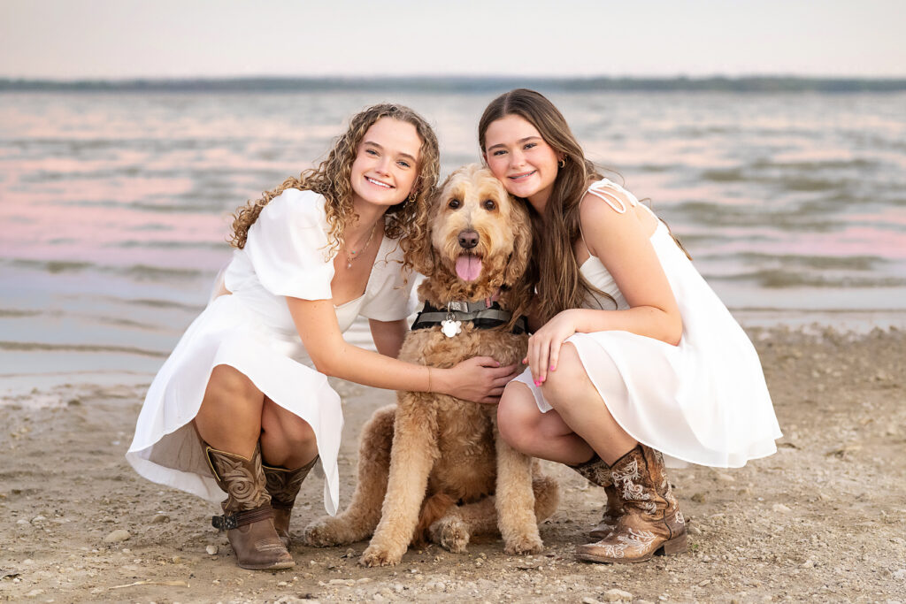 two girls in white dresses with their golden doodle posing for paige walker photography