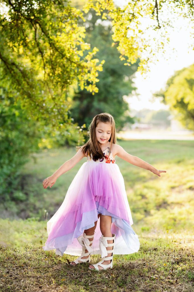 Young girl in a pink tulle dress playing outdoors during a children's portrait session in Fort Worth