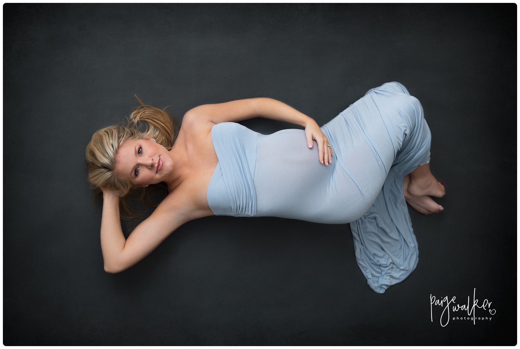 mom to be laying in a blue maternity gown