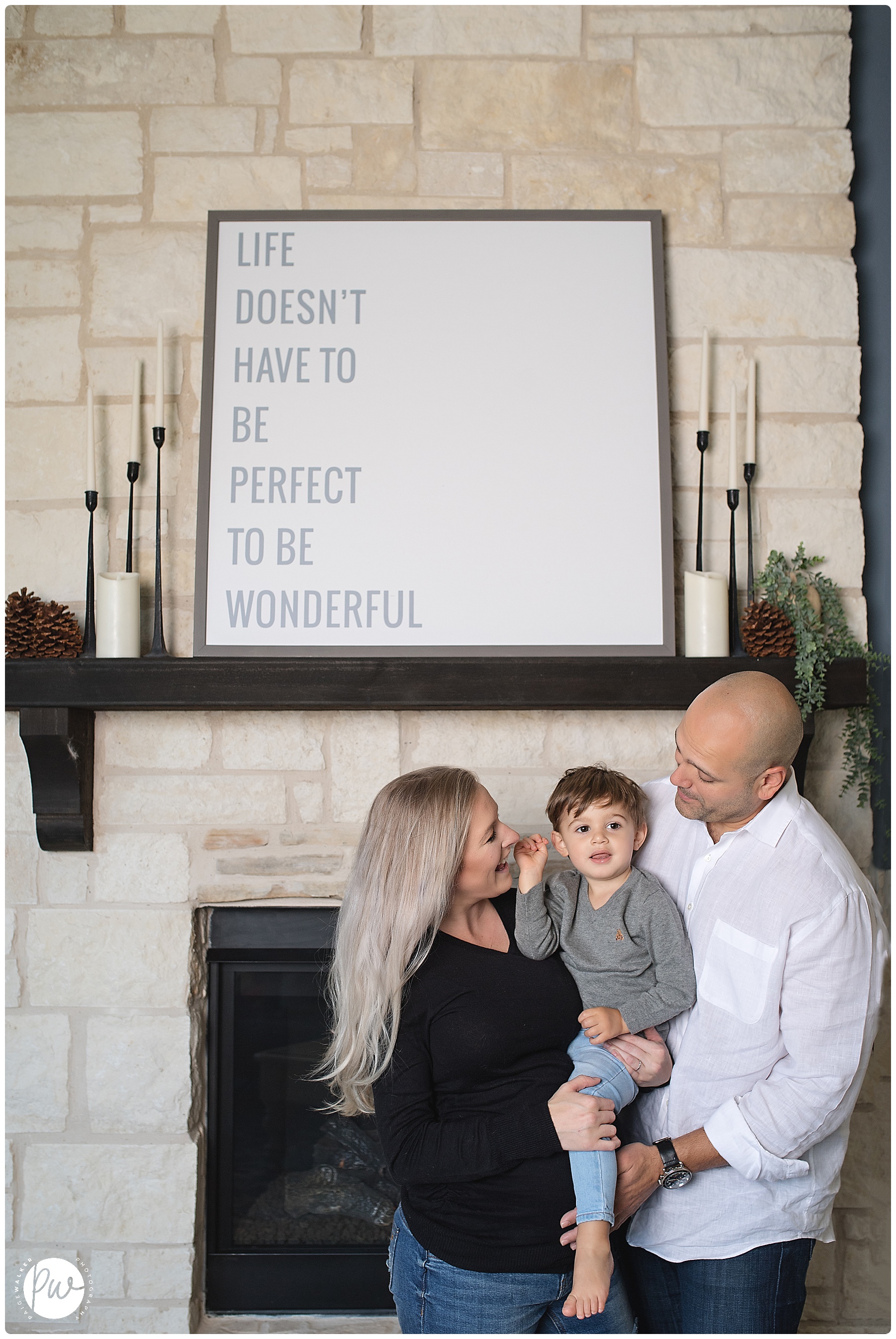 pregnant family standing in front of their home fireplace