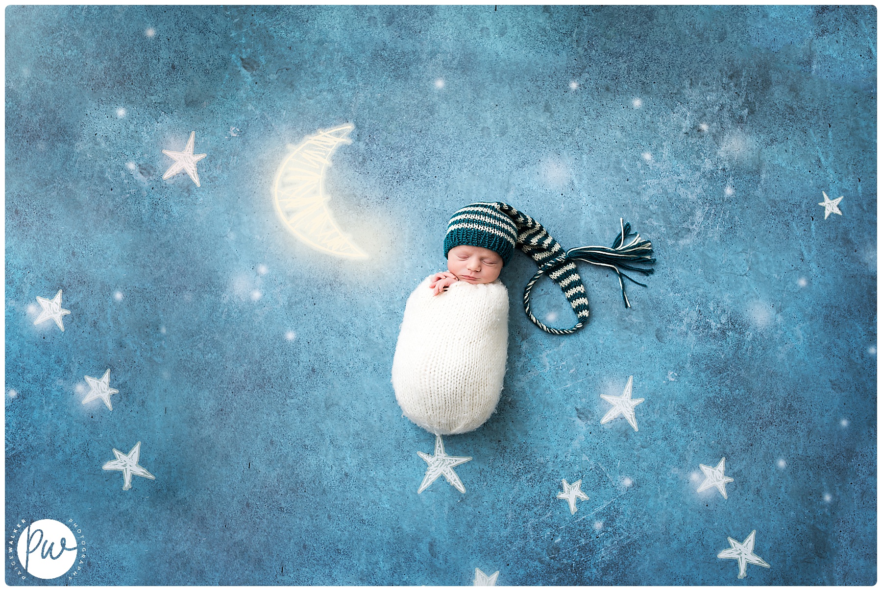 newborn boy wrapped laying by a moon