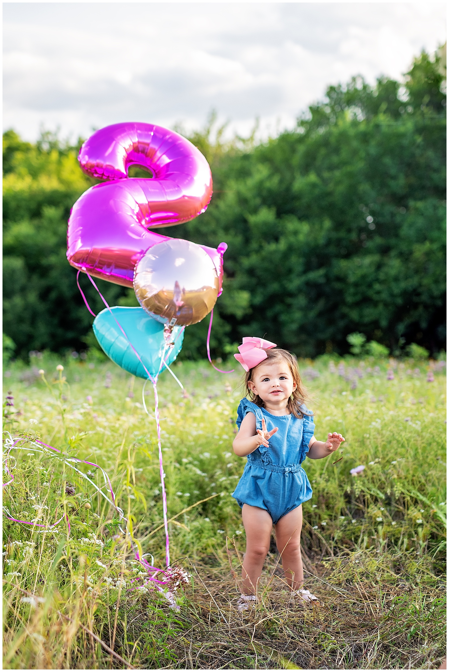 she's turning two with a balloon in the wildflowers