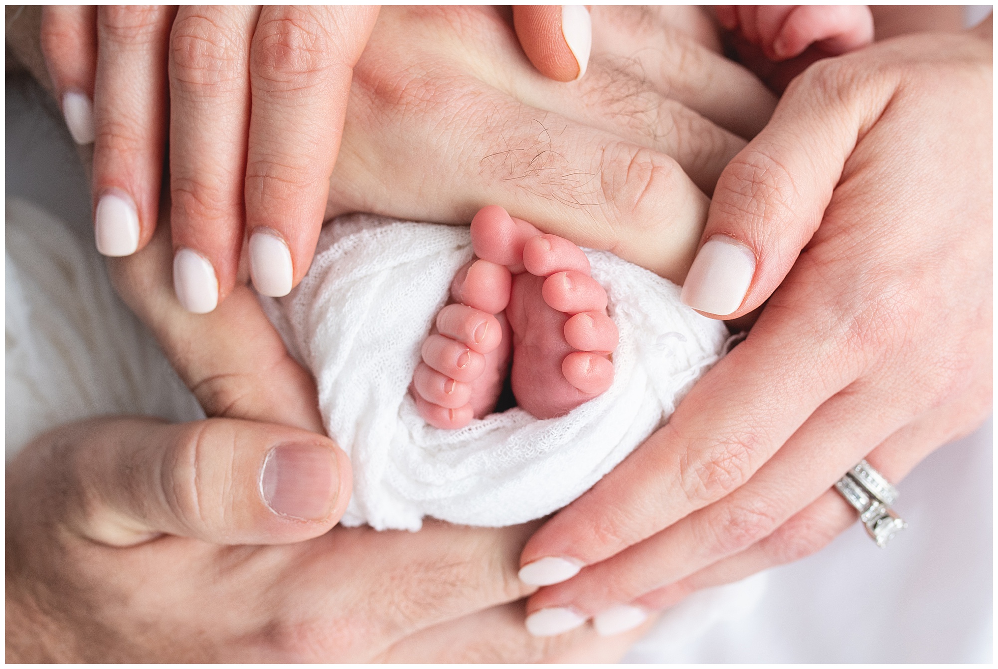 mom, dad and their new baby boy's toes all held together