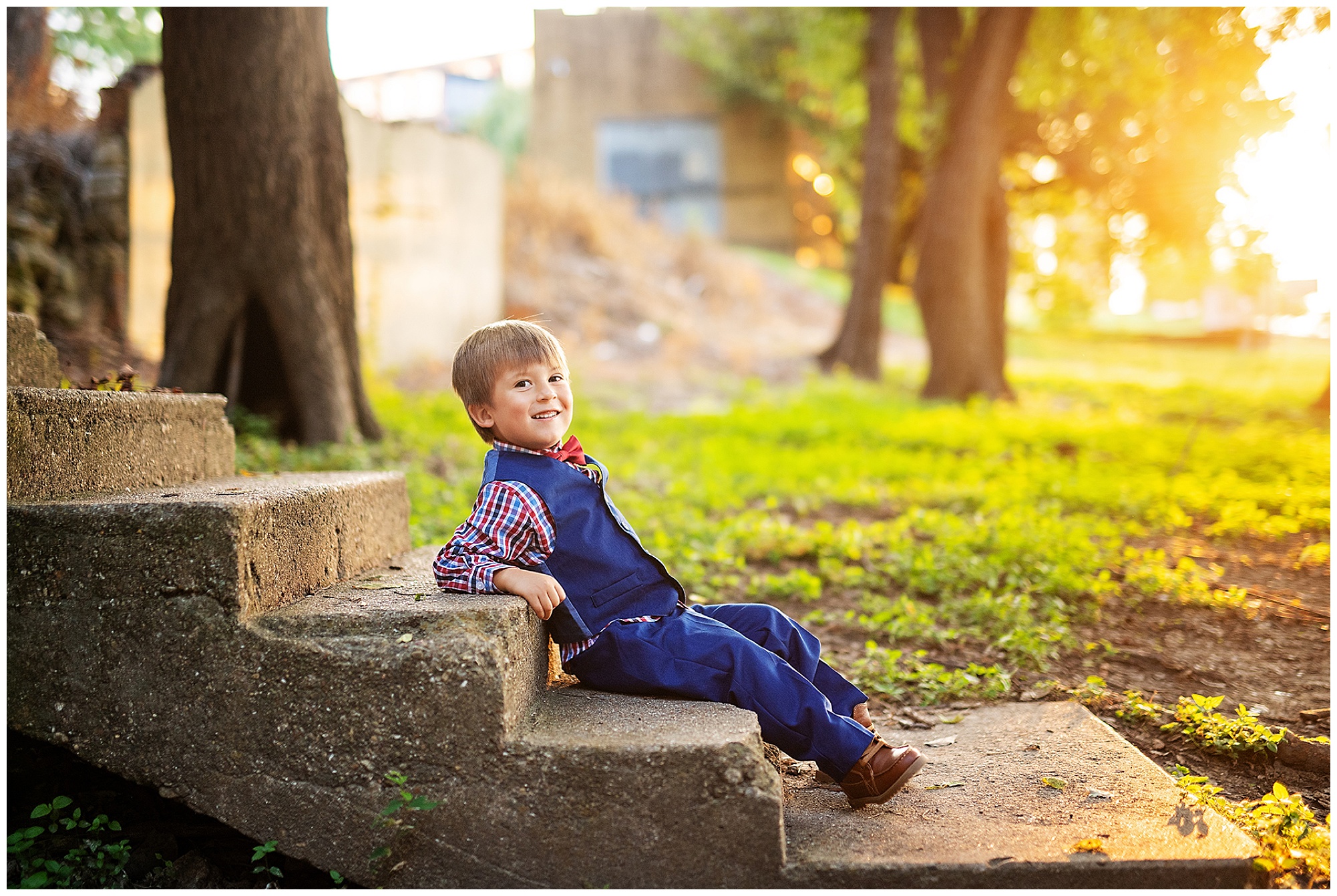 little boy relaxing on concrete stairs in the middle of a field