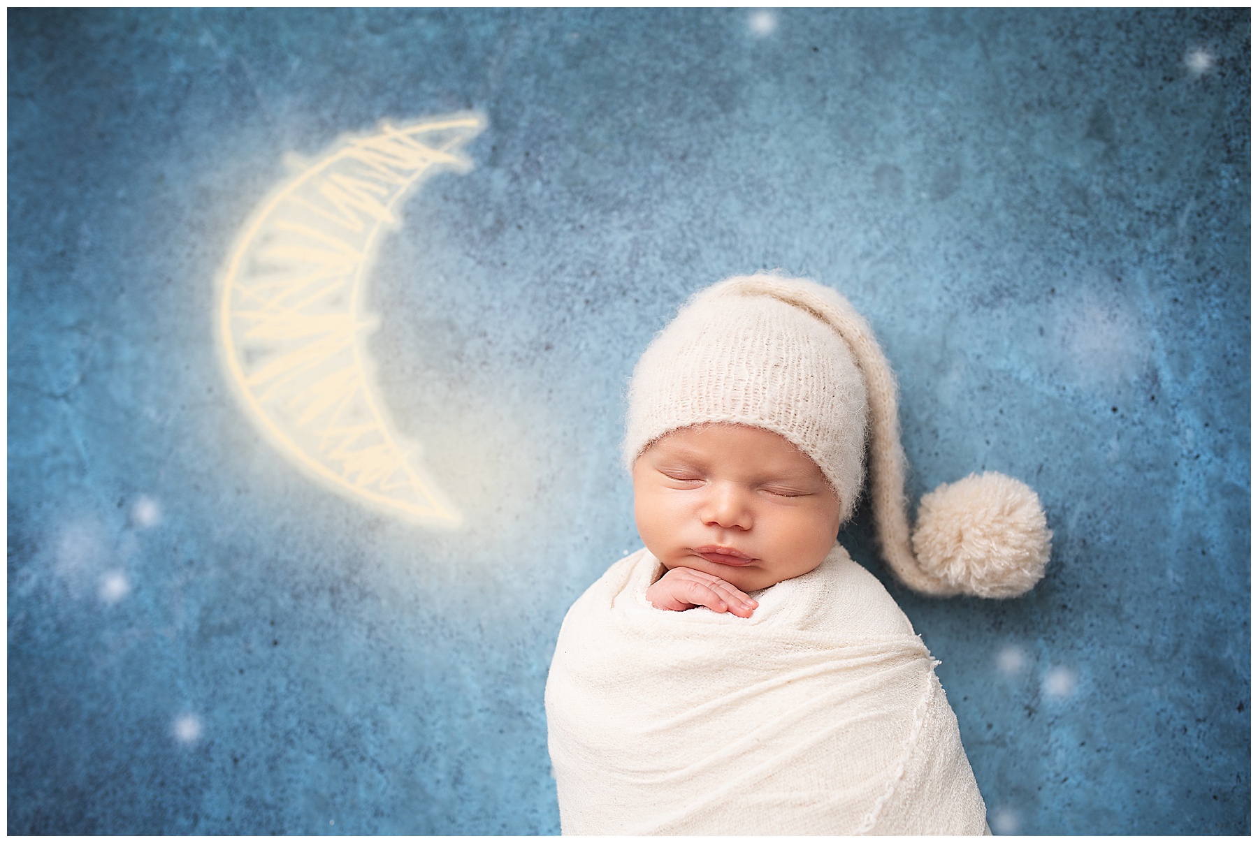 newborn boy laying next to the moon