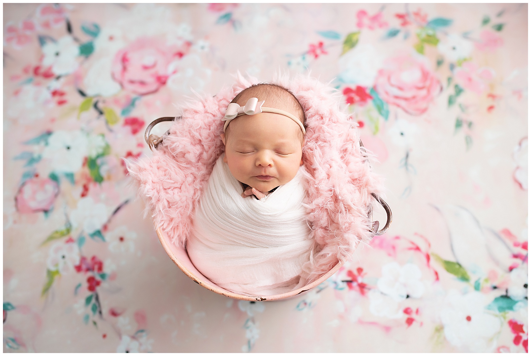 newborn girl sleeping in a pink bucket with lots of pink