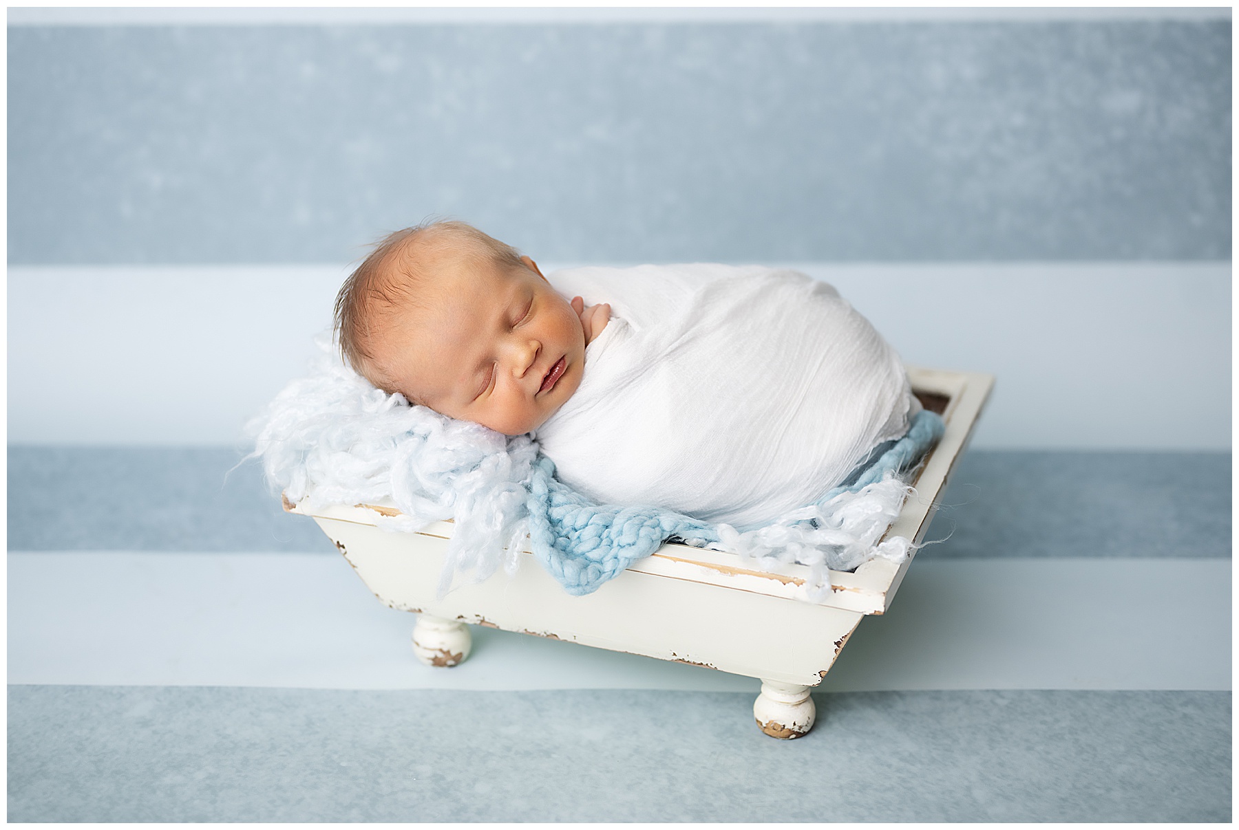 newborn posing in a bucket during a photo session