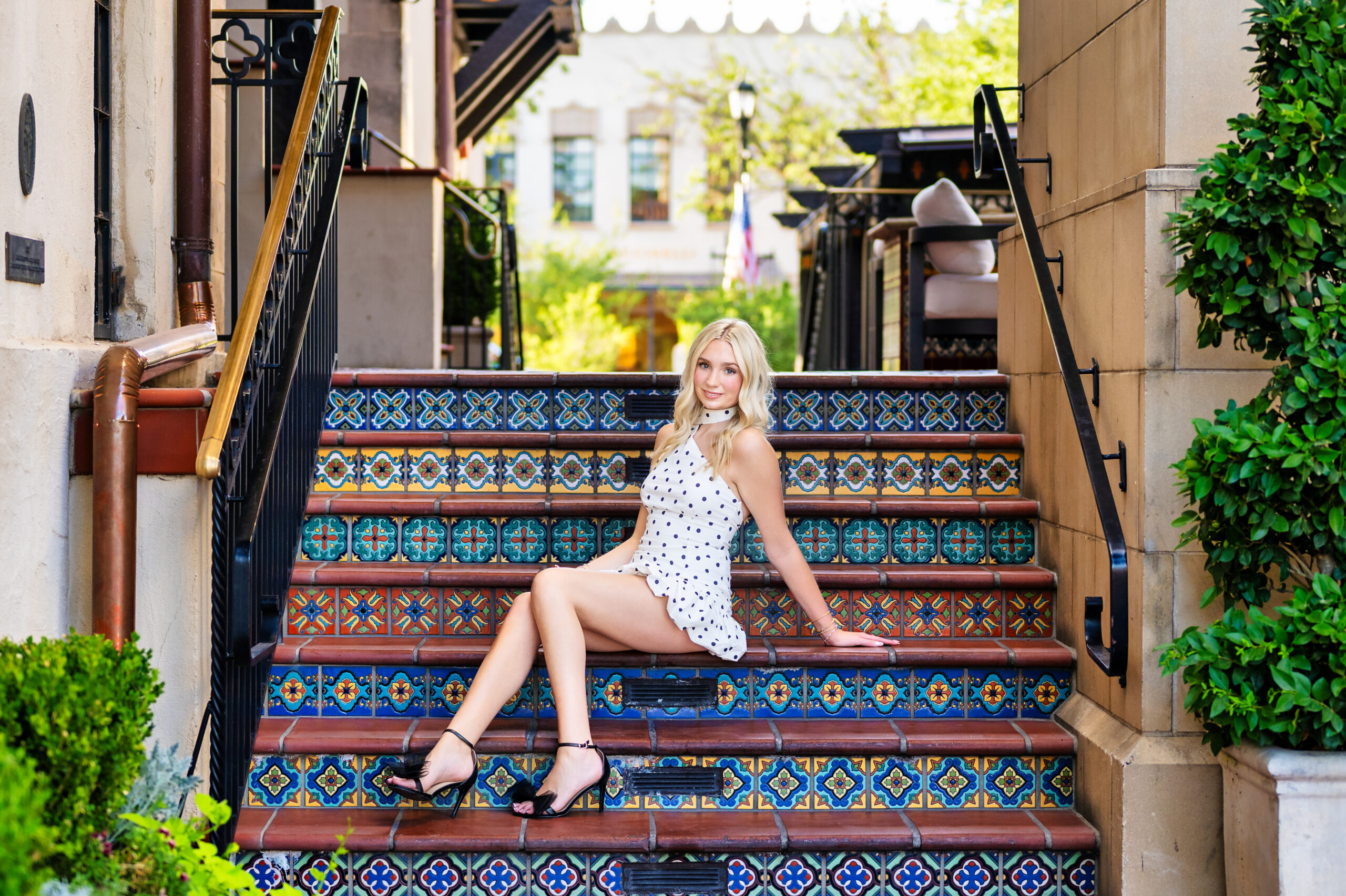 Full-body shot of teen girl sitting on Spanish tile stairs in Highland Park Village, senior session

